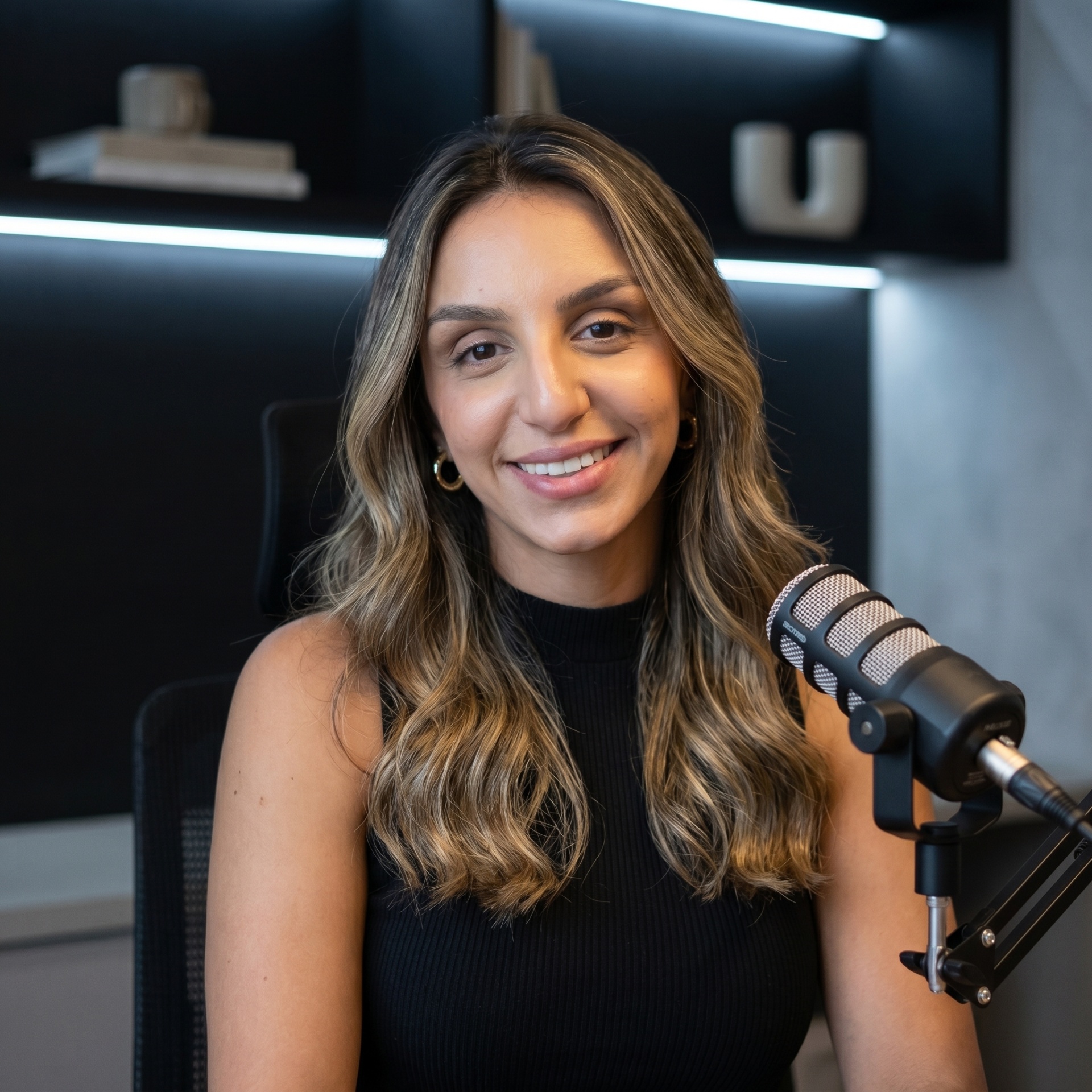Natasha Mohamad sorrindo em estúdio de podcast